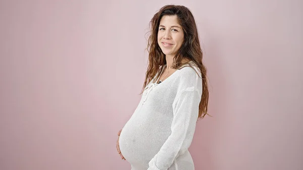 Mladá Těhotná Žena Usmívá Sebevědomě Dotýká Břicho Přes Izolované Růžové — Stock fotografie