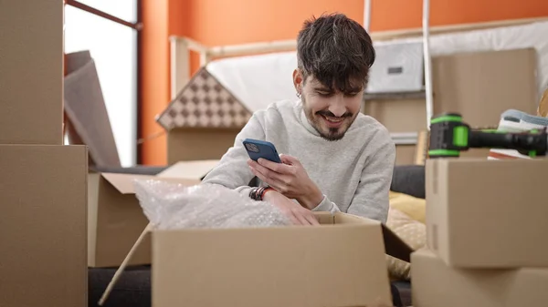 Junger Hispanischer Mann Packt Pappschachtel Mit Smartphone Neuen Zuhause Aus — Stockfoto