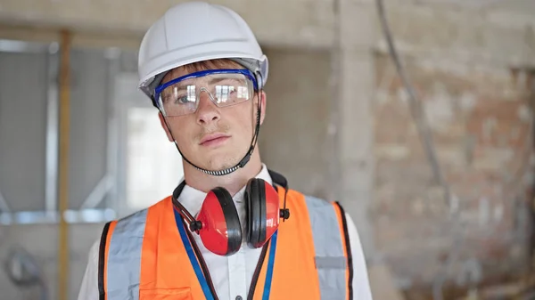 建設現場でリラックスした表情で立つ若い白人男性建築家 — ストック写真