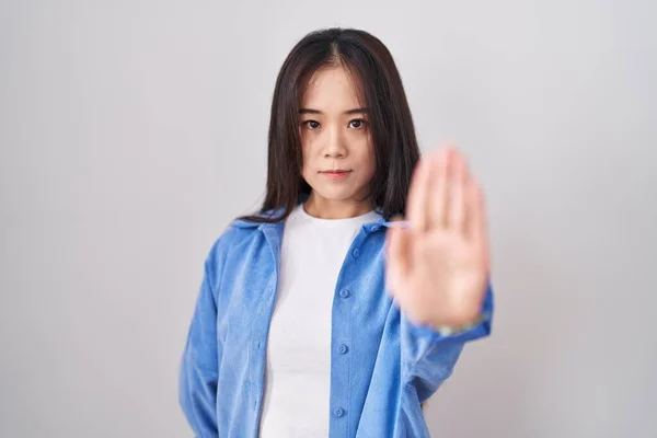 白い背景の上に立つ若い中国人女性は手の手のひらで歌うのを止める 顔に負の重大なジェスチャーで — ストック写真