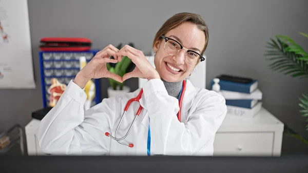 Young Caucasian Woman Doctor Using Computer Doing Heart Gesture Clinic — Stock Photo, Image