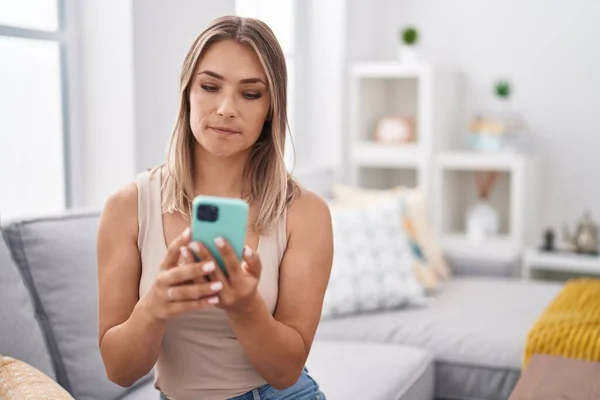 Blonde Caucasian 스마트폰 메시지를 사용하여 소파에 태도와 자신감을 보이는 — 스톡 사진