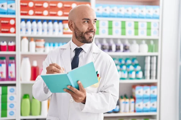 Young Bald Man Pharmacist Smiling Confident Writing Document Pharmacy — Stockfoto