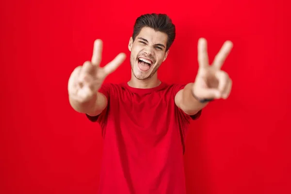 Молодой Латиноамериканец Стоящий Красном Фоне Улыбающийся Показывая Пальцы Обеих Рук — стоковое фото