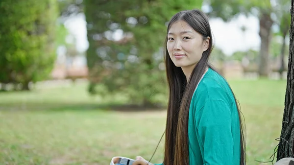 年轻的中国女人拿着耳机在公园里笑 — 图库照片