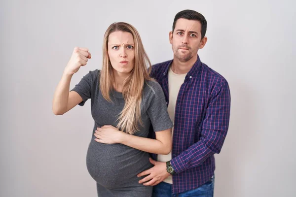Casal Jovem Esperando Bebê Sobre Fundo Branco Irritado Louco Levantando — Fotografia de Stock