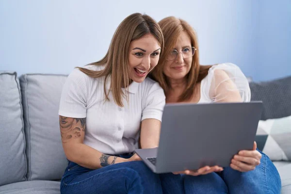 stock image Mother and daughter using laptop sitting on sofa at home