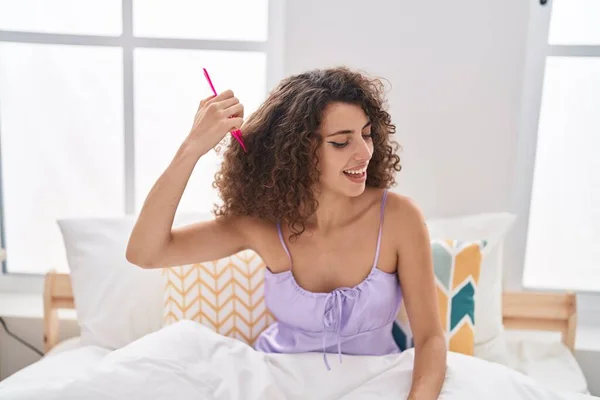 Young Beautiful Hispanic Woman Combing Hair Sitting Bed Bedroom — Stockfoto
