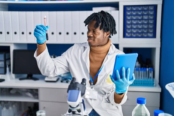 アフリカ系アメリカ人の男性科学者は 実験室でタッチパッド保持試験管を使用して — ストック写真
