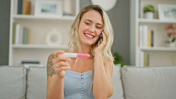 Junge Blonde Frau Spricht Auf Smartphone Und Hält Schwangerschaftstest Lächelnd — Stockfoto