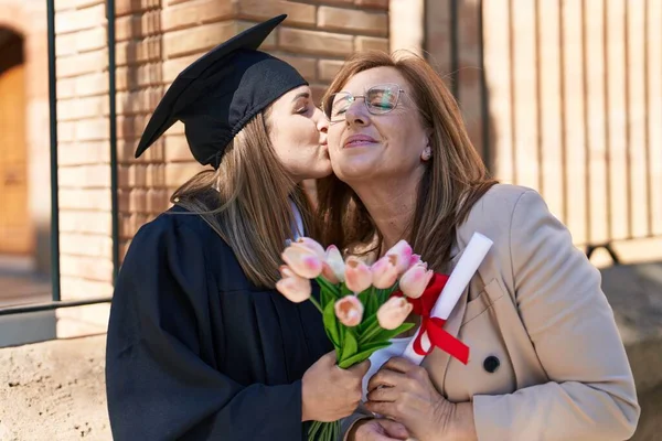 母親と娘はお互いを抱き合って卒業式と花を大学で開催 — ストック写真