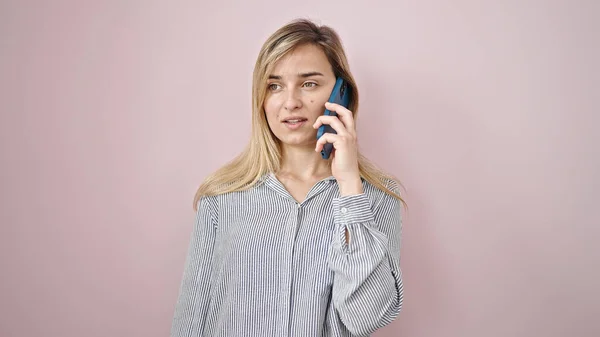 若いですブロンド女性Talk上のスマートフォンで深刻な表現上の隔離されたピンクの背景 — ストック写真