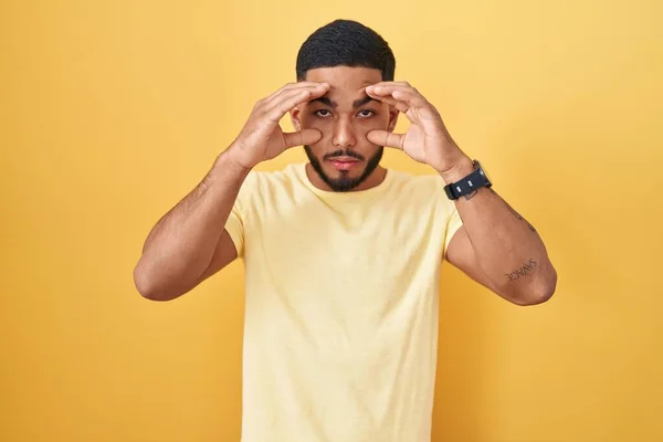 Young Hispanic Man Standing Yellow Background Trying Open Eyes Fingers — Stock Photo, Image