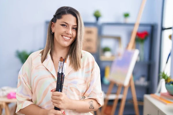 Young Hispanic Woman Artist Smiling Confident Holding Paintbrushes Art Studio — ストック写真
