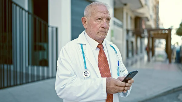 Senior Doctor Canoso Pie Con Expresión Seria Usando Smartphone Calle — Foto de Stock