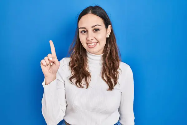 Young Hispanic Woman Standing Blue Background Showing Pointing Finger Number — Stockfoto