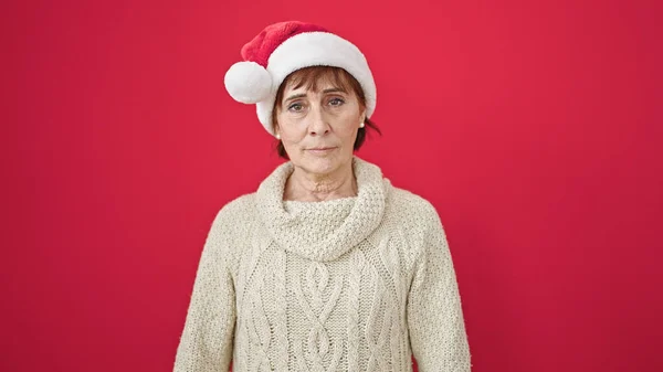 Зрелая Латиноамериканка Стоящая Серьезным Выражением Лица Рождественской Шляпе Изолированном Красном — стоковое фото