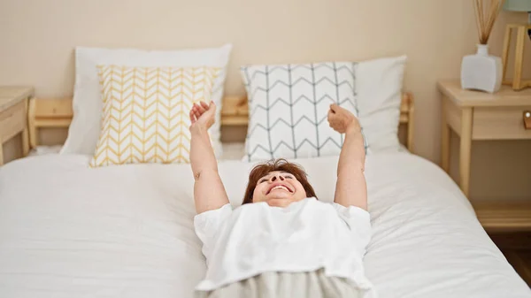 Μεσήλικη Γυναίκα Χαμογελά Αυτοπεποίθηση Ξαπλωμένη Στο Κρεβάτι Τεντώνοντας Χέρια Στην — Φωτογραφία Αρχείου