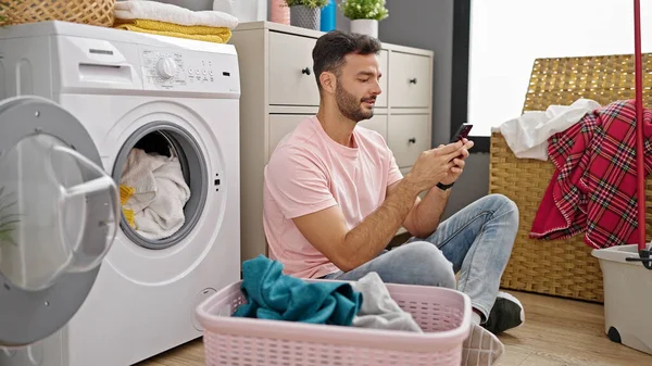 Ung Latinamerikan Man Med Smartphone Tvätta Kläder Tvättstuga — Stockfoto