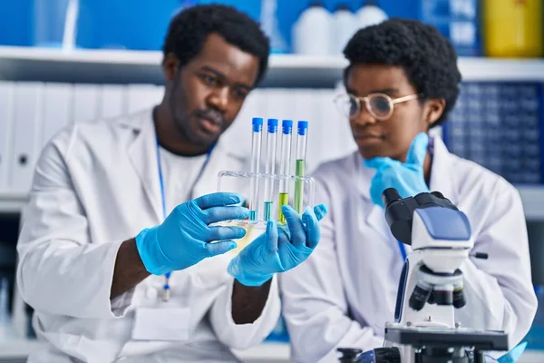 アフリカ系アメリカ人の男性と女性科学者が実験室で試験管を持っている — ストック写真
