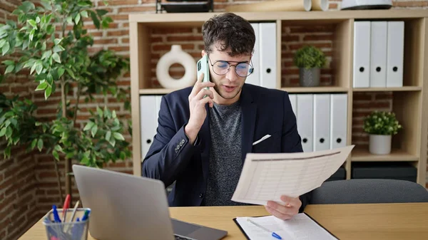 Νεαρός Ισπανός Επιχειρηματίας Που Μιλάει Στο Τηλέφωνο Διαβάζοντας Στο Γραφείο — Φωτογραφία Αρχείου