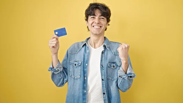 Mladý Hispánec Drží Kreditní Kartu Vítězným Výrazem Nad Izolovaným Žlutým — Stock fotografie