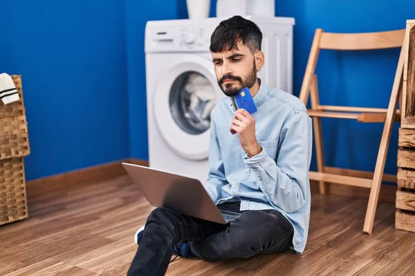Young Hispanic Man Using Laptop Credit Card Waiting Washing Machine —  Fotos de Stock