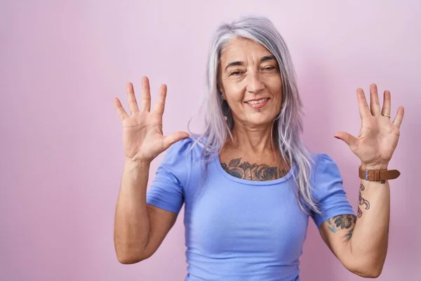 Középkorú Tetoválásokkal Áll Rózsaszín Háttér Mutatja Rámutatva Ujjak Száma Miközben — Stock Fotó