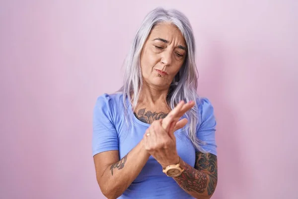 粉红背景上有纹身的中年妇女手和手指疼痛 关节炎发炎 — 图库照片