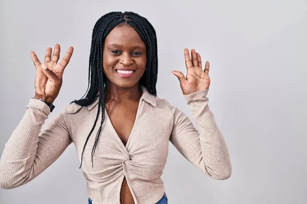 非洲女人头上戴着辫子 站在白色的背景上 用9号手指指尖 面带微笑 自信而快乐 — 图库照片