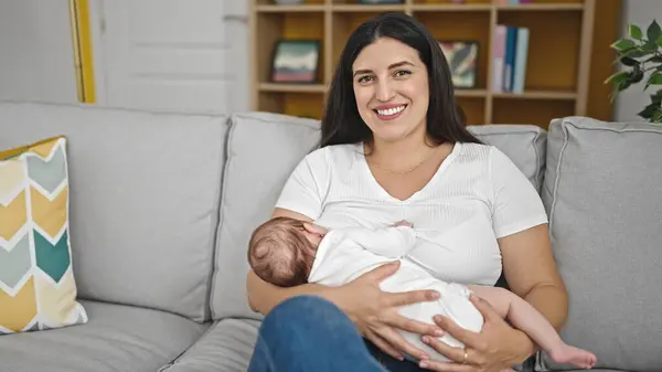 自宅でソファーで授乳している母と赤ちゃんの娘 — ストック写真