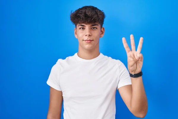 Латиноамериканец Стоящий Синем Фоне Показывающий Пальцами Номер Три Улыбаясь Уверенно — стоковое фото