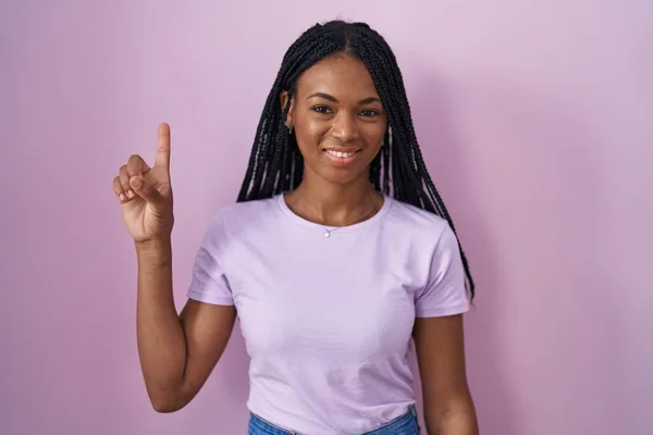 Африканська Американська Жінка Косами Стоїть Над Рожевим Тлом Показуючи Вказуючи — стокове фото