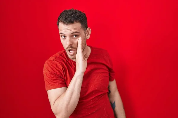 Ung Latinamerikansk Man Står Över Röd Bakgrund Hand Mun Berättar — Stockfoto