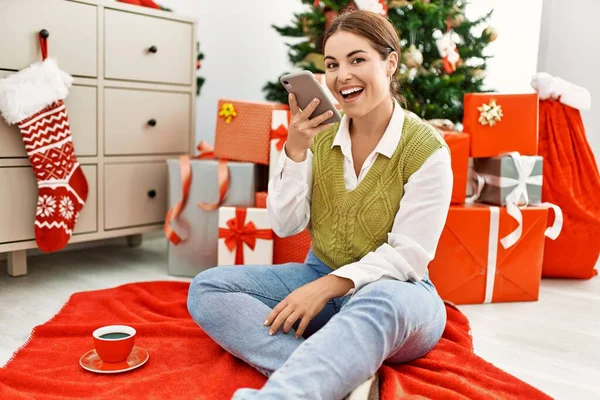 Young Beautiful Hispanic Woman Talking Smartphone Sitting Christmas Tree Home — Stock fotografie