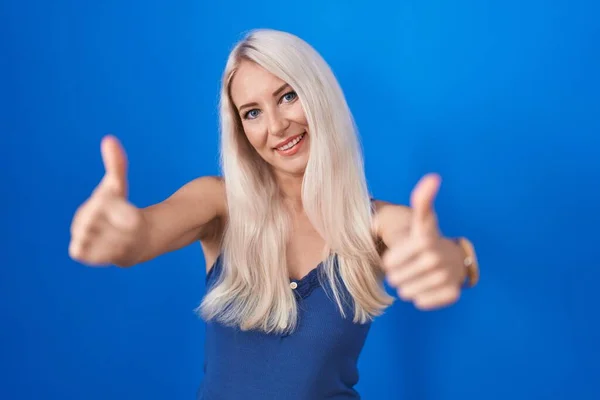 Biała Kobieta Stojąca Nad Niebieskim Tłem Aprobująca Pozytywny Gest Ręką — Zdjęcie stockowe