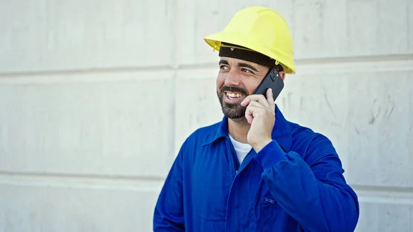 在建筑工地 他的年轻员工戴着安全帽 用智能手机说话 — 图库照片
