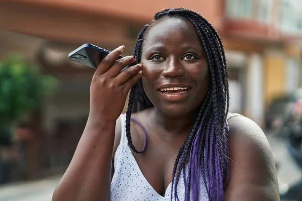 アフリカ系アメリカ人女性がコーヒーショップのテラスでスマートフォンの音声メッセージを聞いて自信を持って笑っている — ストック写真