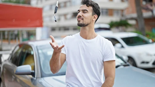 若いヒスパニックの男は自信を持って路上で空気に新しい車の鍵を投げる — ストック写真