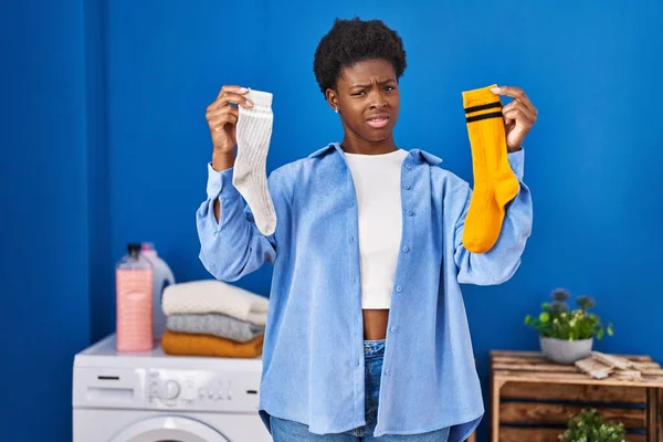Mujer Afroamericana Sosteniendo Calcetines Limpios Sucios Expresión Despistada Confusa Concepto —  Fotos de Stock