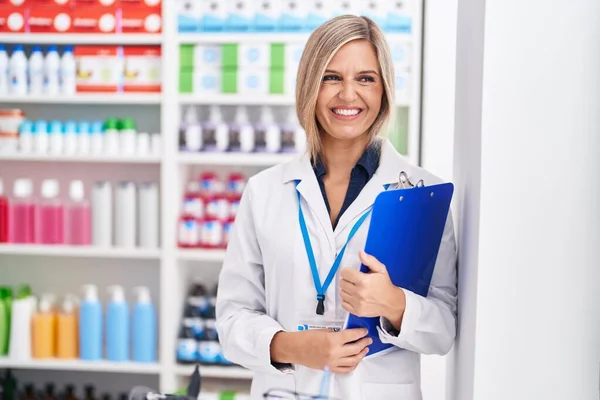 Joven Mujer Rubia Farmacéutica Sonriendo Confiado Sujetando Portapapeles Farmacia — Foto de Stock