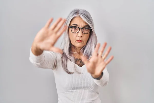 中年妇女灰白的头发站在白色的背景上 用手和手指头 镜头透视画框 — 图库照片