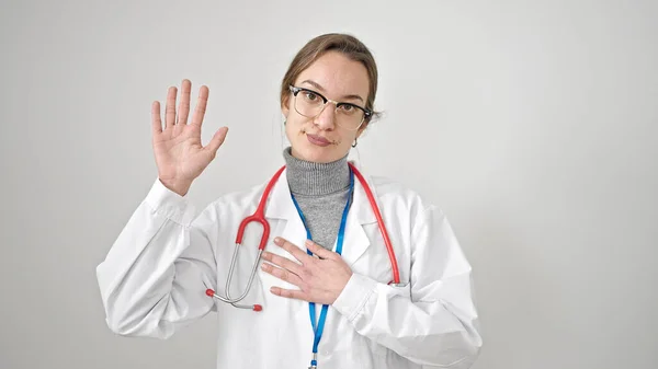 年轻的高加索女医生 手托着胸膛在孤立的白色背景下宣誓 — 图库照片