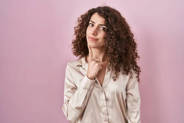 Pembe Arka Planda Duran Kıvırcık Saçlı Spanyol Kadın Parmak Çenesinde — Stok fotoğraf