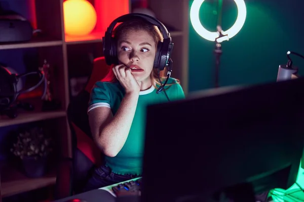 口が爪をかむ上で手でストレスと緊張を見てビデオゲームをプレイしている赤毛の女性 不安の問題 — ストック写真