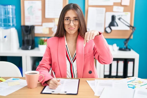 在办公室里工作的这位惊慌的年轻女人戴着眼镜 低着头看起来很伤心很沮丧 用手指指示方向 很不高兴 很沮丧 — 图库照片