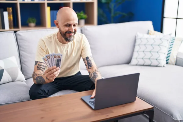 Young Bald Man Using Laptop Holding Dollars Home — Foto de Stock