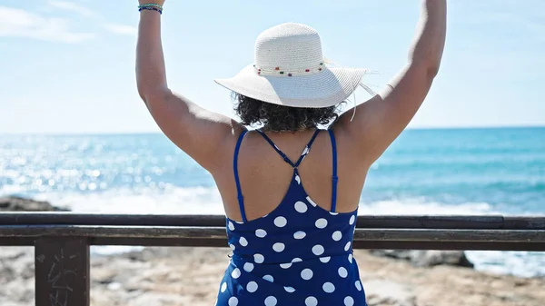 若いです美しいですラテン女性観光身に着けています夏の帽子ストレッチ腕で海辺 — ストック写真