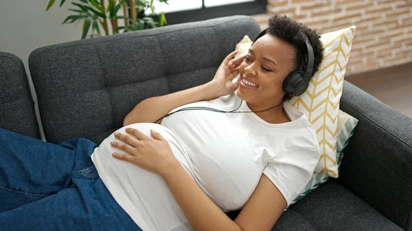 Молодая Беременная Женщина Слушает Музыку Лежащую Дома Диване — стоковое фото