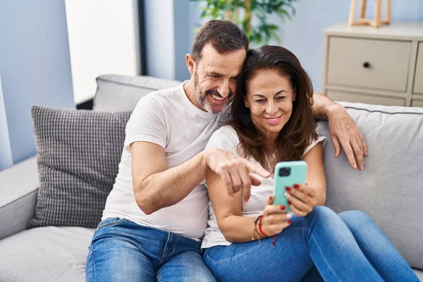 中年男性と女性カップル使用スマートフォン座って上のソファに家 — ストック写真